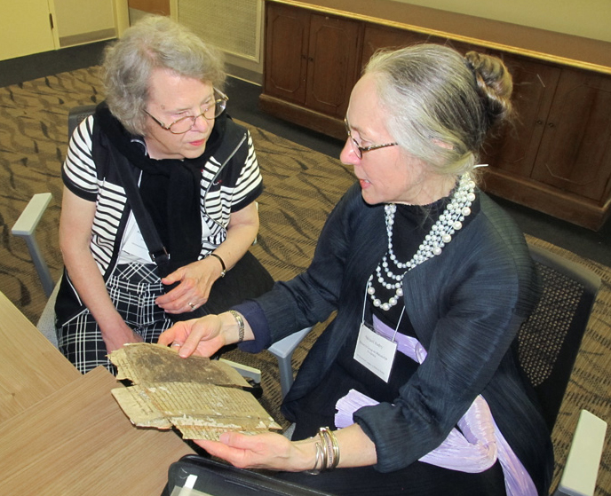 Two manuscript scholars confer about a manuscript fragment, brought to the event by request, at the 2015 Reception at the 50th International Congress on Medieval Studies. Photography by David Sorenson