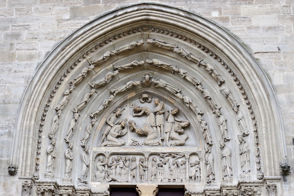 Architectural sculpture of the Tympanum and Archivolt of the North Transept Portal at the Basilica of Saint-Denis, including a representation of the decapitation of the saint. Photo Myrabella via Wikimedia Commons.