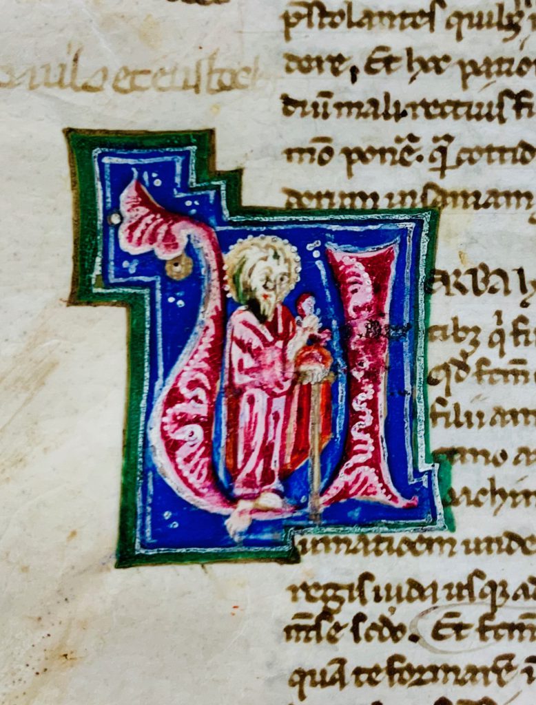 The painted Initial letter U encloses a standing figure of a standing male saint with a halo.